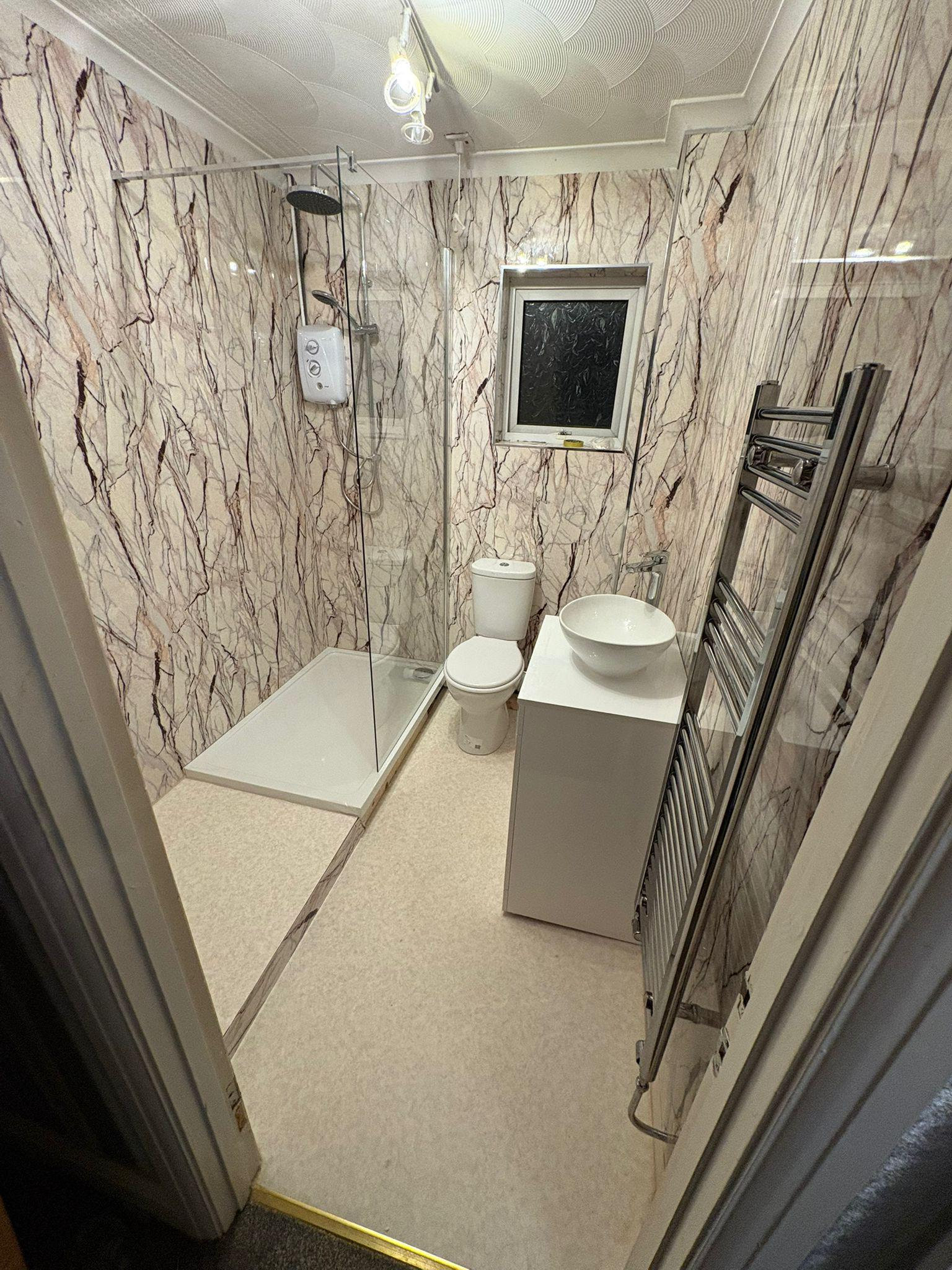 Fully refitted shower room with marble-effect wall panels, walk-in shower and vanity basin