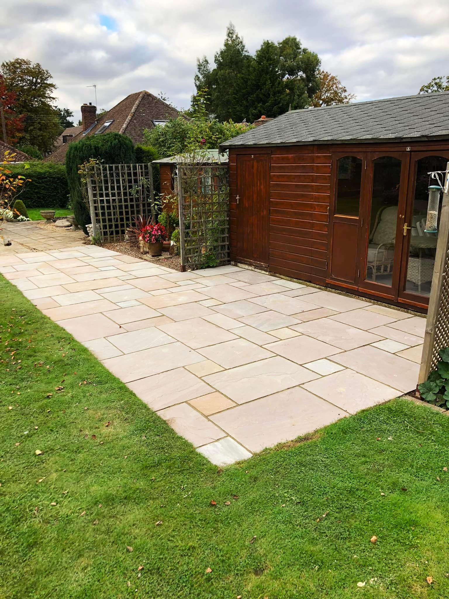 Newly laid Indian sandstone patio beside a garden summerhouse, completed by Roseland Maintenance